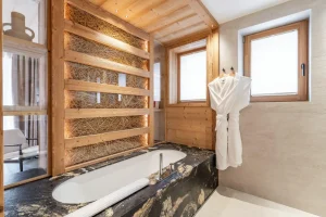Master suite bathroom with a black stone bathtub and a walk-in shower at Chalet Brigues in Courchevel Le Praz