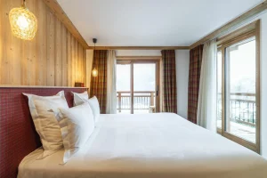 Bedroom with a double bed, a burgundy headboard and an oval mirror at Chalet Brigues in Courchevel Le Praz