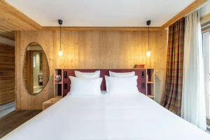Double bedroom with a dressing room, wardrobes and a red headboard at Chalet Brigues in Courchevel Le Praz