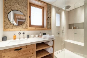Bathroom with a washbasin, a round mirror and a walk-in shower at Chalet Brigues in Courchevel Le Praz