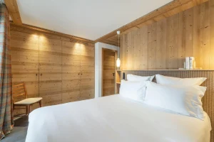 Double bedroom with built-in wardrobes and a white bed at Chalet Brigues in Courchevel Le Praz