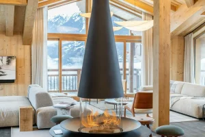 Central wood-burning fireplace with a brazier design, surrounded by stools at Chalet Brigues in Courchevel Le Praz