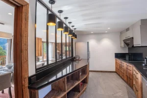 Kitchen with a black bar, wooden shelving and pendant lights at Chalet du Plantin in Méribel Village