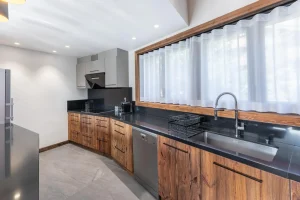 Kitchen with reclaimed-wood units, a black worktop, a sink and a dishwasher at Chalet du Plantin in Méribel Village