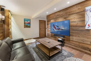 TV lounge with a sofa, a coffee table and reclaimed-wood panelling at Chalet du Plantin in Méribel Village