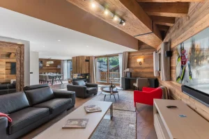 Lounge under exposed beams with leather sofas, red armchairs and a view onto the balcony at Chalet du Plantin in Méribel Village