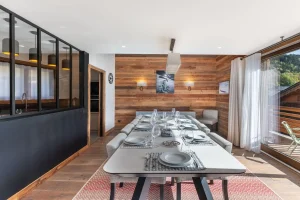 Laid dining table facing the fireplace and the kitchen's glazed partition at Chalet du Plantin in Méribel Village