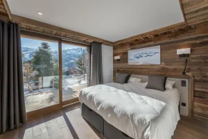 Bedroom with a double bed and a sliding glazed door opening onto the terrace at Chalet du Plantin in Méribel Village
