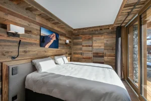 Bedroom with a double bed, a grey headboard and a wall-mounted screen at Chalet du Plantin in Méribel Village