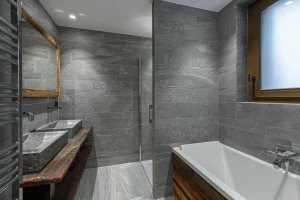 Grey stone bathroom with a bathtub, a shower and a double washbasin at Chalet du Plantin in Méribel Village