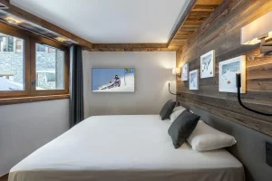 Double bedroom with a king-size bed, a grey headboard and ski posters at Chalet du Plantin in Méribel Village