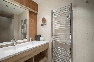Shower room with a double washbasin, a towel radiator and a glass shower at Chalet Églantine in Courchevel La Tania