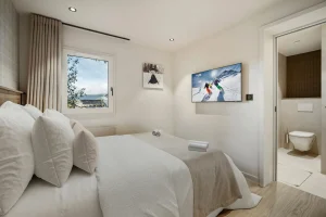 Double bedroom with a wooden headboard, tartan wallpaper and a wall-mounted TV at Chalet Églantine in Courchevel La Tania