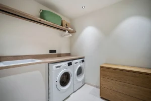 Laundry room with a washing machine, a tumble dryer and a wooden worktop at Chalet Églantine in Courchevel La Tania