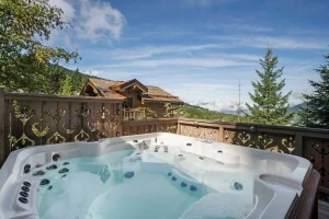 Outdoor hot tub on a carved timber terrace, with views of the forest and the mountains at Chalet Églantine in Courchevel La Tania