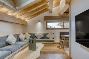 Lounge with a grey banquette, a coffee table and a wall-mounted TV at Chalet Épicéa in Les Saisies