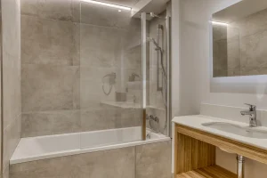 Bathroom with a bathtub, shower screen and washbasin at Chalet Épicéa in Les Saisies