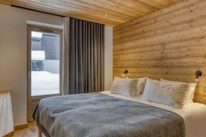 Light wood bedroom with a double bed and a French door at Chalet Épicéa in Les Saisies