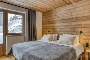 Bedroom with a double bed, a wooden headboard and a window at Chalet Épicéa in Les Saisies