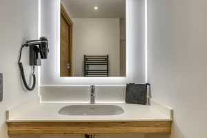 Shower room with a washbasin, an illuminated mirror and a towel radiator at Chalet Épicéa in Les Saisies
