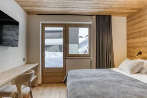 Bedroom with a desk, a TV and a French door at Chalet Épicéa in Les Saisies
