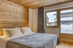 Bedroom with a double bed and grey curtains by the French door at Chalet Épicéa in Les Saisies