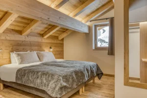 Bedroom under exposed beams with a large bed at Chalet Épicéa in Les Saisies