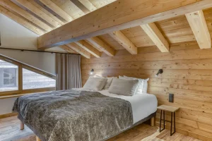 Attic bedroom with a bed and light wood beams at Chalet Épicéa in Les Saisies