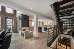 Living area with a central fireplace, a metal staircase and access to the wellness level at Chalet Merlin in Saint-Martin-de-Belleville