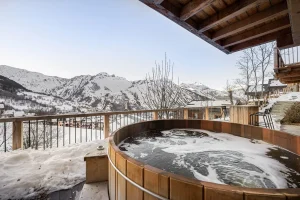 Wooden Nordic bath on the terrace with views of the snow-covered mountains at Chalet Merlin in Saint-Martin-de-Belleville