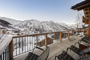 Timber terrace with sun loungers and views of the village and valley at Chalet Merlin in Saint-Martin-de-Belleville