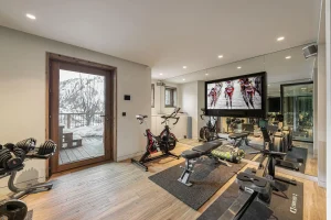 Gym with an exercise bike, rowing machine, weights bench, dumbbells and a screen at Chalet Merlin in Saint-Martin-de-Belleville