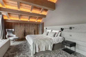Master suite with a designer armchair, a bench and a wooden dressing area at Chalet Merlin in Saint-Martin-de-Belleville