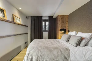 Double bedroom with a king-size bed, blackout curtains and framed photographs at Chalet Merlin in Saint-Martin-de-Belleville