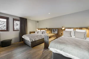 Family bedroom with two double beds and a reclaimed-wood headboard at Chalet Merlin in Saint-Martin-de-Belleville