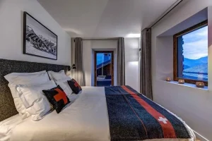 Bedroom with a king-size bed, a red and navy blanket and a window with a view of the valley