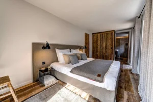 Bedroom with a grey throw, a headboard with reading lights and reclaimed-wood panelling