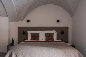 Bedroom with a vaulted stone ceiling and a red-striped blanket