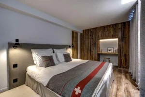 Bedroom with a red-striped blanket, a reclaimed-wood headboard wall and a desk