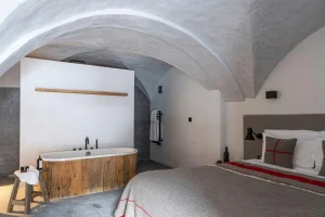 Bedroom with an arched stone ceiling and a freestanding bath behind the bed