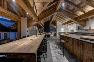 Dining table and kitchen island with stools, under exposed timber rafters