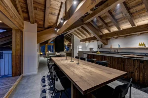 Long timber dining table with bar stools beside the kitchen counter