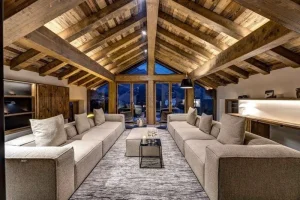 Long living area with two cream sofas facing each other under a vaulted timber roof