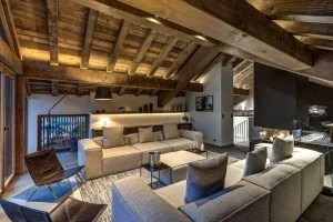 Mezzanine lounge with cream sofas and a staircase, under sloping timber rafters
