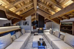 Lounge with cream sofas, a see-through fireplace and a bar beyond, under roof beams