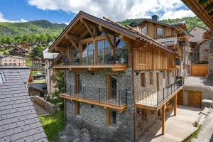 Chalet Villette's stone and timber façade with balconies, in the summer sun