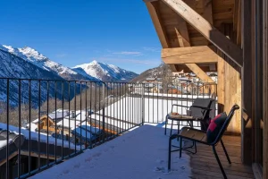 Balcony with chairs and a view of the mountains and village in winter